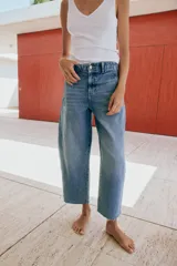 Jeans de tiro medio con pernera holgada tipo barrel que se estrecha hacia el tobillo, acabado con bajo sin costura, bolsillos delanteros y bolsillos de plastrón en la espalda. Cierre frontal con cremallera y botón.