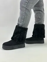 Botas negras de caña media con plataforma y detalle de piel sintética en la parte superior.