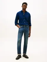 Camisa de corte slim color azul con textura dobby, manga larga, cuello abotonado y cierre frontal con botones blancos. Presenta el logo bordado de Tommy Hilfiger en el pecho.