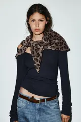 Bandana de forma triangular confeccionada en hilatura con lana, con estampado animal print en tonos marrones y cierre ajustable con ojal.