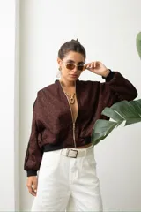 Campera tipo bomber de gamuza con estampado animal print en tonos bordó y negro. Presenta cierre frontal dorado, puños y cintura elástica en color negro, y detalle de franjas laterales en las mangas.