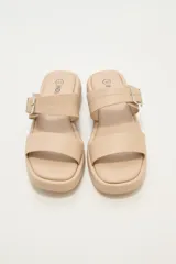 Sandalia de plataforma plana color beige, con dos tiras anchas en el empeine, una de ellas con hebilla metálica ajustable.