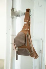 Riñonera negra de cuero vacuno con correa regulable, cierre superior con doble cremallera y bolsillo frontal con cremallera.