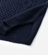 Chaleco de punto sin mangas con escote en V y aberturas laterales. Presenta una textura de tejido trenzado y un corte alargado, ideal para superposiciones.