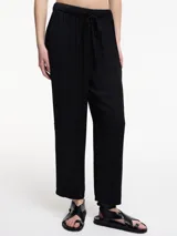 Pantalón negro de corte recto y largo cropped, con cintura elástica ajustable mediante lazo.