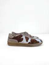 Championes de cuero con estampado de vaca en blanco y marrón, con cordones y suela de goma color beige.