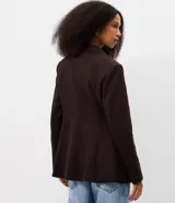 Blazer de sastrería marrón oscuro de corte ajustado, con solapa clásica, bolsillos con solapa en los laterales y cierre frontal cruzado con dos botones.