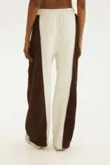 Pantalón jogging de corte recto y tiro mid, con cintura elástica. Presenta un diseño bicolor con panel central en color crudo y laterales en marrón oscuro, separados por una línea delgada en tono celeste claro.