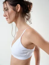 Bralette de algodón rib, color beige, de diseño triangular sin aro, con tirantes finos regulables y banda elástica bajo el busto con la marca grabada.