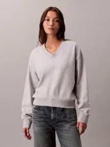Buzo Calvin Klein de tejido terry color gris melange, con cuello en V, manga larga y costura vertical central en el frente.
