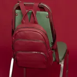 Mochila de tamaño mediano confeccionada en símil cuero color beige, con doble bolsillo frontal con cierre metálico, asa de mano superior y correas regulables de cinta tejida.