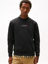 Buzo de cuello redondo Tommy Hilfiger, color negro, confeccionado en algodón regenerativo. Presenta cuello, puños y bajo acanalados, con el logo gráfico distintivo de la marca estampado en el centro del pecho y la bandera bordada en la manga.