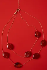 Collar doble de cadena dorada fina con cuentas marmoladas en tonos ámbar de formas orgánicas.