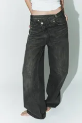 Jeans de tiro alto con diseño de pierna ancha y corte extra largo. Presenta una cintura cruzada asimétrica con cierre de cremallera y botones metálicos, además de un diseño clásico de cinco bolsillos.