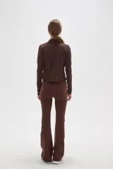 Campera deportiva de ajuste entallado, confeccionada en poliéster color gris oscuro. Presenta cuello alto, cierre frontal completo y mangas largas con aberturas para los pulgares.