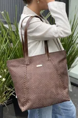 Bolso grande tipo tote color beige con textura tejida y costuras decorativas en los laterales. Tiene doble asa de hombro y logo de la marca en el frente. Interior forrado con bolsillo con cierre y portacelular.