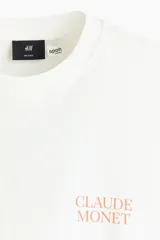 Remera de algodón de corte holgado con cuello redondo y hombros caídos. Presenta un estampado minimalista con el nombre Claude Monet en el pecho.