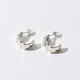 Aros tipo argolla plateados con diseño ondulado.