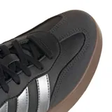 Championes urbanos Adidas modelo Barreda T, color negro con detalles en gris metalizado y suela de goma color marrón. Presentan el diseño clásico de las tres tiras laterales y refuerzos en la puntera.