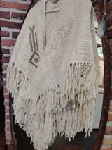 Ruana color crema tejida en lana merino con bordados a mano sobre lino.