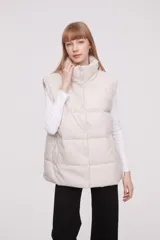 Chaleco acolchado color marfil con cuello alto y cierre frontal con botones a presión.