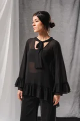 Blusa negra de tul transparente con mangas largas acampanadas con volados, detalle de lazo tipo corbata en el cuello y volado en el ruedo.