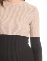 Vestido corto de tejido de punto acanalado, con diseño color block en tono arena jaspeado en la parte superior y negro en la parte inferior. Tiene cuello redondo y mangas largas.