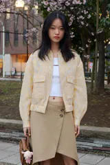 Chaqueta tipo bomber de cuello redondo y manga larga, confeccionada en tejido jacquard con diseño floral en tonos dorados y crema. Presenta cierre frontal con cremallera, bolsillos delanteros de plastrón con solapa y puños y bajo elásticos.