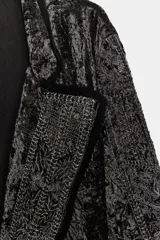 Kimono largo de terciopelo con cuello solapa, manga larga y cinturón ajustable del mismo tejido. Presenta bordados con hilo metalizado, bolsillos laterales ocultos y acabados desflecados.