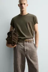 Camiseta de algodón color verde oliva, corte regular fit, con cuello redondo y manga corta. Presenta un pequeño corazón bordado en la manga.