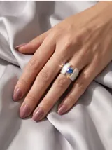 Anillo ancho de plata y oro con textura granulada y piedra circonia central de color azul.