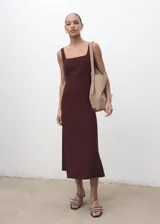 Vestido midi color bordó con diseño evasé, tirantes anchos y cuello cuadrado. Presenta costuras decorativas verticales y cierre de cremallera en la parte posterior.