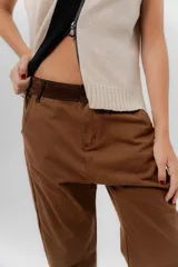 Pantalón de gabardina azul marino, de corte barrel y tiro bajo, con detalles en pana marrón en la pretina y en el ruedo interior vuelto.