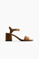 Sandalias de gamuza color marrón tostado, con taco de bloque medio, punta cuadrada, tira delantera ancha y tira al tobillo con hebilla metálica dorada.