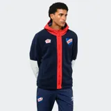 Campera de polar azul marino con capucha, cierre frontal y detalles en rojo. Presenta mangas con paneles blancos, logo de Umbro bordado y escudo del Club Nacional de Football.