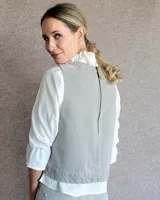 Chaleco de corte recto y largo a la cintura, confeccionado en denim con estampado de rayas verticales en tonos azul y blanco. Presenta cuello redondo y costuras visibles que definen su estructura.