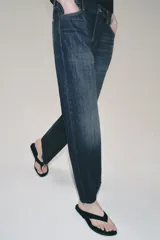 Jeans de tiro bajo con corte loose leg y largo tobillero. Presenta diseño de cinco bolsillos, cierre frontal con cremallera y botón, y acabado con efecto lavado.