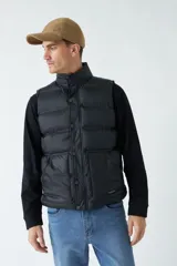 Chaleco color camel de nylon con cierre frontal con broches a presión, cuello alto y bolsillos laterales.