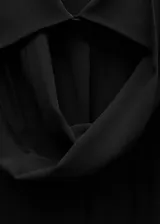 Camisa de tejido fluido y semitransparente, con cuello camisero, cierre frontal de botones, mangas largas con puños abotonados y lazo integrado en el cuello. Presenta un diseño recto con aberturas laterales en el bajo.