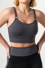 Top deportivo de color azul francia, con escote redondo, breteles finos ajustables y detalle de aros metálicos en la unión de los breteles con el frente. Presenta una faja ancha de doble tela en la base para mayor soporte.