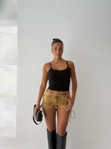 Short de jean color ocre con cordones cruzados en la parte delantera, cierre de cremallera en los laterales y corte ajustado.