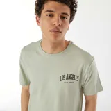 Camiseta verde con cuello redondo y estampado con la frase "Los Angeles U.S. of America" en el pecho.