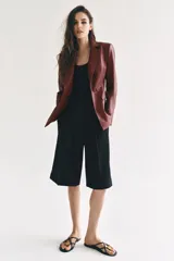 Blazer de cuero sintético en color beige, con cuello solapa, manga larga y bolsillos con solapa en el frente. Cierre frontal cruzado con botones a tono.