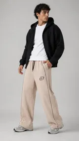Pantalón jogger de felpa color beige con costuras decorativas y ribetes oscuros a lo largo de las piernas, cintura elástica con cordón ajustable y pequeño logo bordado en el muslo.