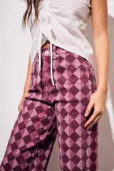 Jean de corte baggy y tiro medio, con estampado de rombos en tonos violeta y borravino. Presenta diseño de cinco bolsillos y cierre frontal con botón y cremallera.