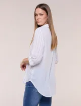 Camisa de calce holgado en género liviano con estampado a rayas verticales, cuello camisero clásico y abotonadura frontal a tono. Presenta mangas largas regulables con presilla y botón para ajustar a tres cuartos, espalda con canesú y suave pliegue central, y ruedo curvo estilo camisero.