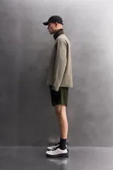 Camiseta relaxed fit de color verde militar, confeccionada en tejido con estructura waffle. Tiene cuello redondo, manga larga con puño elástico y un bolsillo plastrón con cierre de cremallera en el pecho.