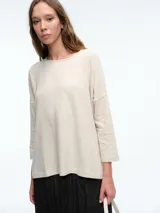 Buzo tejido de silueta relajada con sisa caída y tajos laterales. Presenta cuello redondo y mangas tres cuartos.