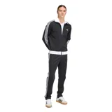 Pantalón deportivo Adidas modelo Beckenbauer, color negro con las icónicas tres rayas blancas laterales y logo del trébol bordado. Confeccionado en tejido de piqué, presenta corte entallado, bolsillos laterales con cierre y cintura con cordón de ajuste.