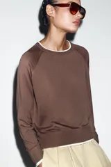 Jersey de punto efecto doble, color azul marino con detalles en blanco en el cuello, puños y ruedo. Presenta cuello redondo y manga larga con diseño de hombros raglán.
